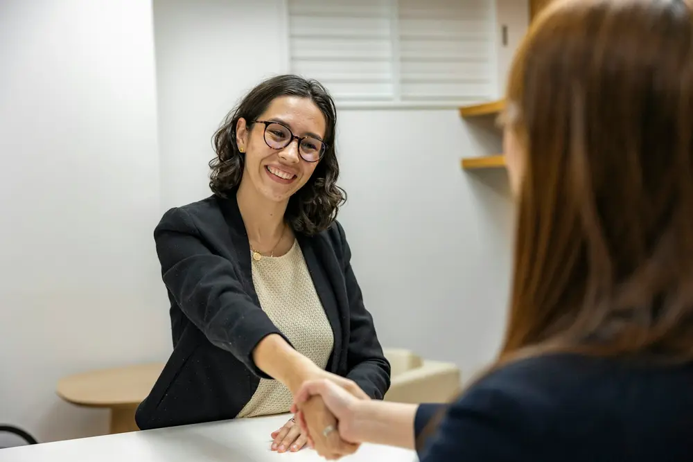 Corretora apertando a mão de uma cliente após a reunião